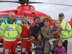The family of a patient assembles for a photograph  by the helicopter
