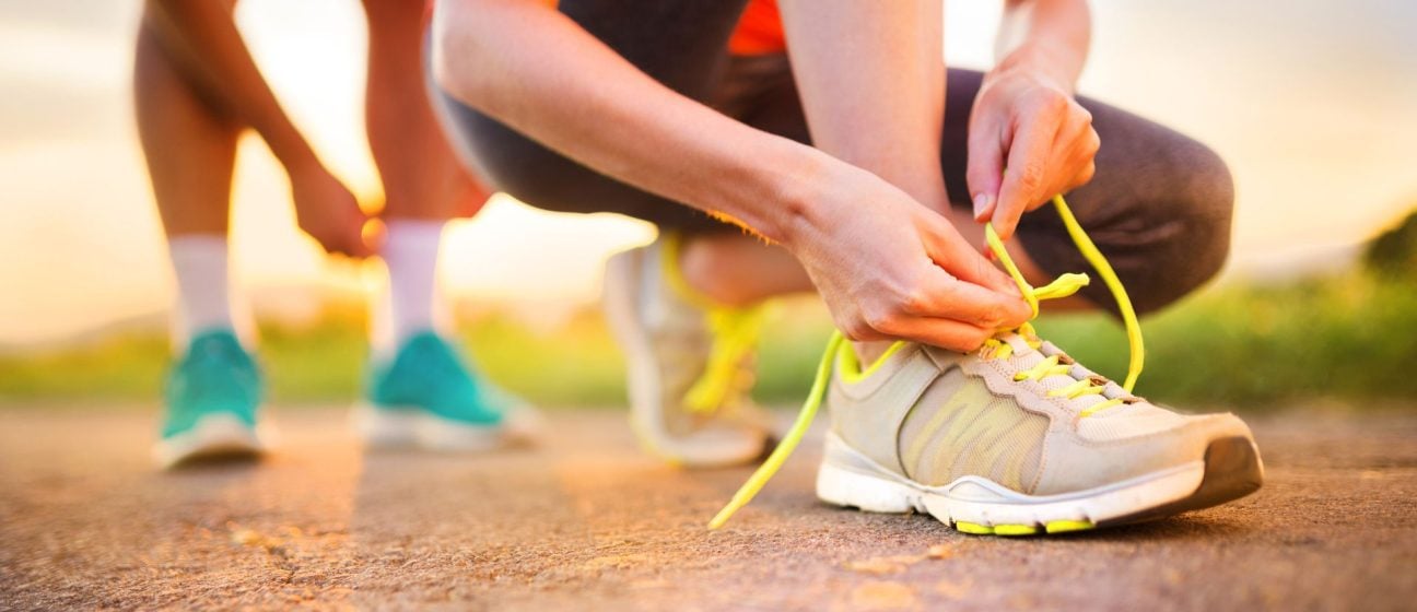 Person tieing up shoe lace on road