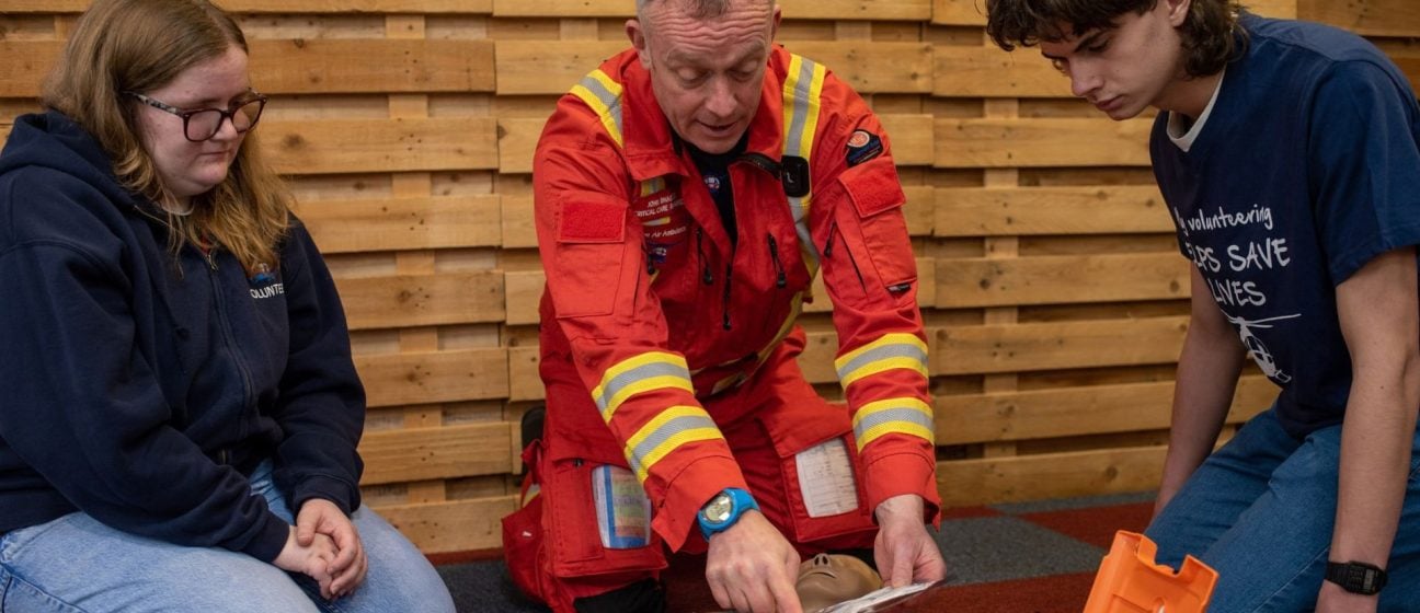 A Devon Air Ambulance crew member teachers volunteers how to use a defibrillator