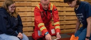 A Devon Air Ambulance crew member teachers volunteers how to use a defibrillator